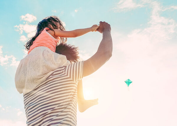 Father with daughter playing with kite and having fun on the beach - Dad enjoying time with his kid outdoor - Family relationship and love concept - Focus child body - Sunset colors tones filter