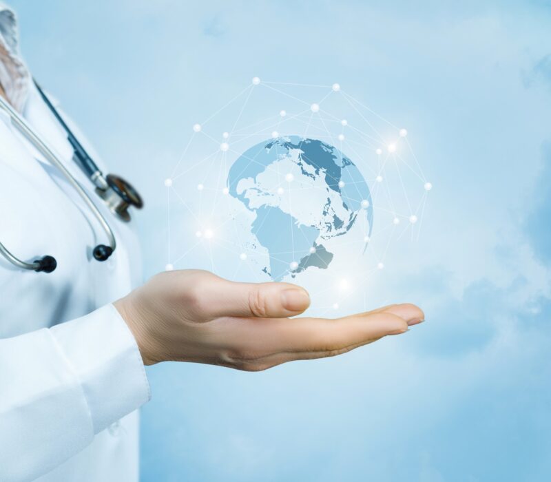 A female doctor with a stethoscope on her neck is holding a crystal, sparkling global map on her hand .